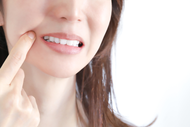 口を指さす女性